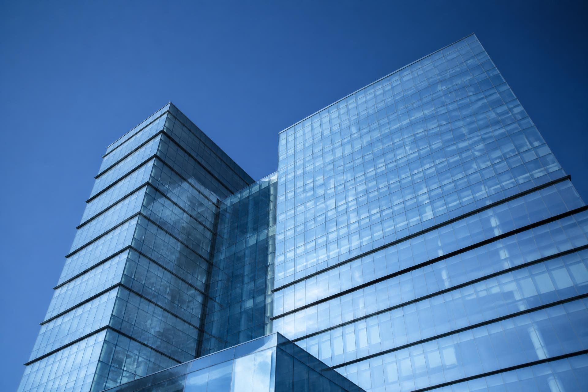 Modern glass commercial office tower against a deep blue sky